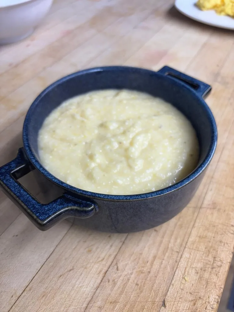 Warm creamy Southern-style cheesy grits served in a blue ceramic dish at Estime's Cafe Colonia NJ